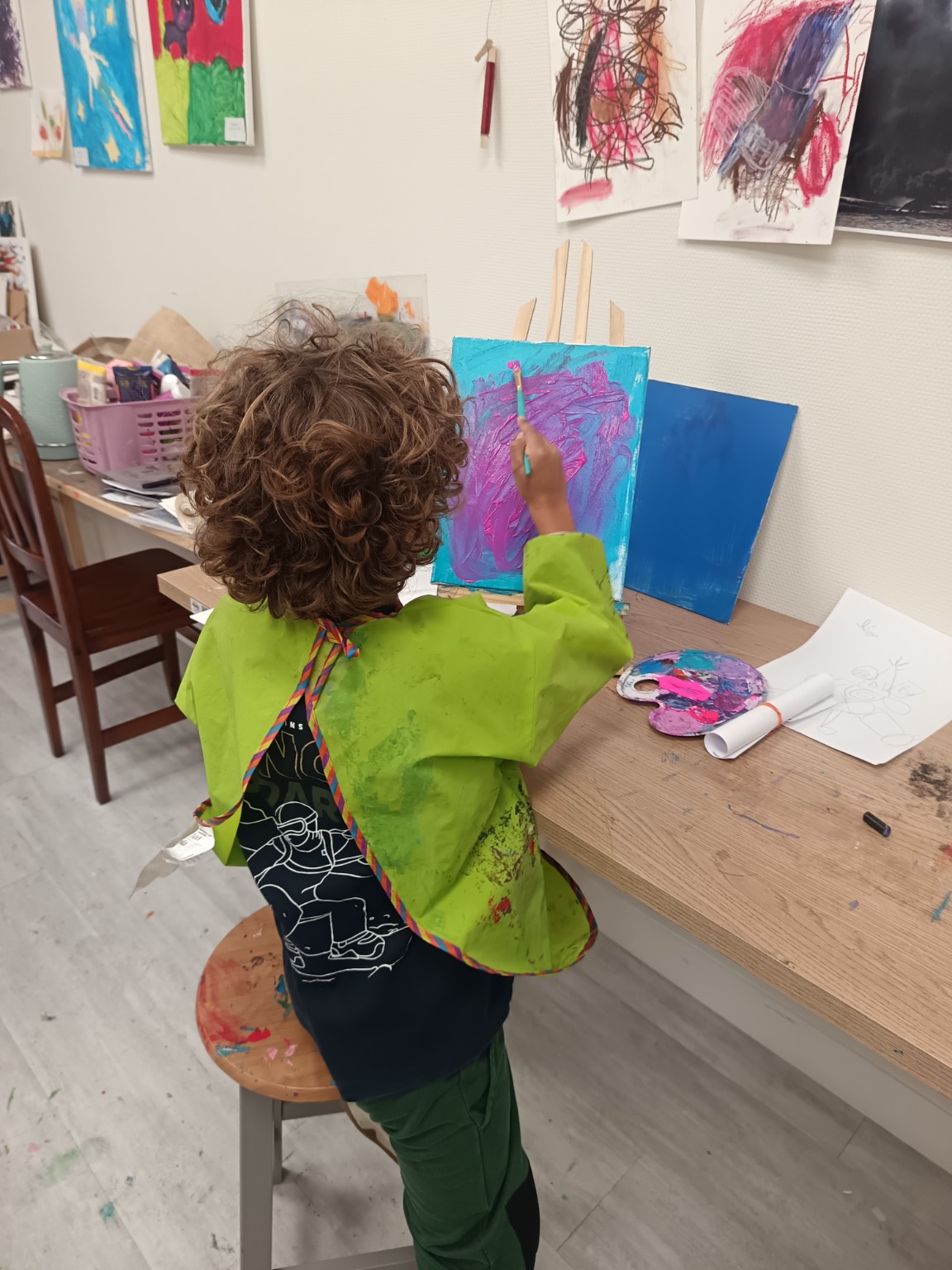 Jeune élève peignant une toile abstraite rose et bleue à l'atelier Narin'Art