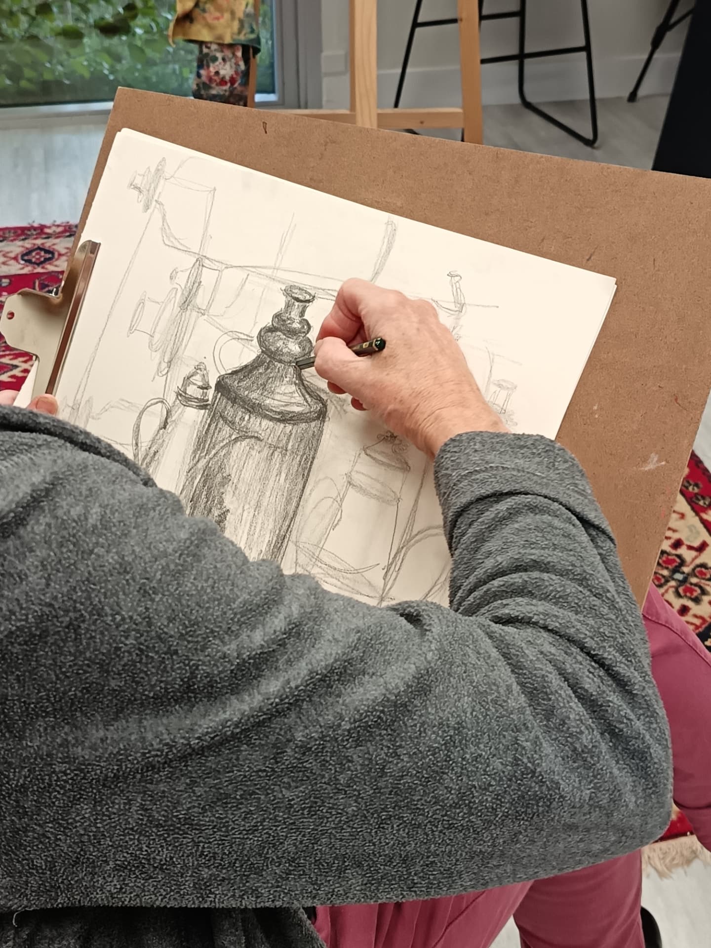 Élève dessinant une nature morte au crayon lors d'un cours de dessin