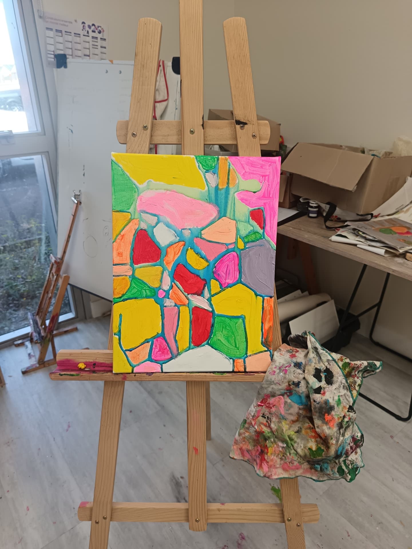 Toile abstraite en mosaïque de couleurs vives peinte par un élève sur chevalet