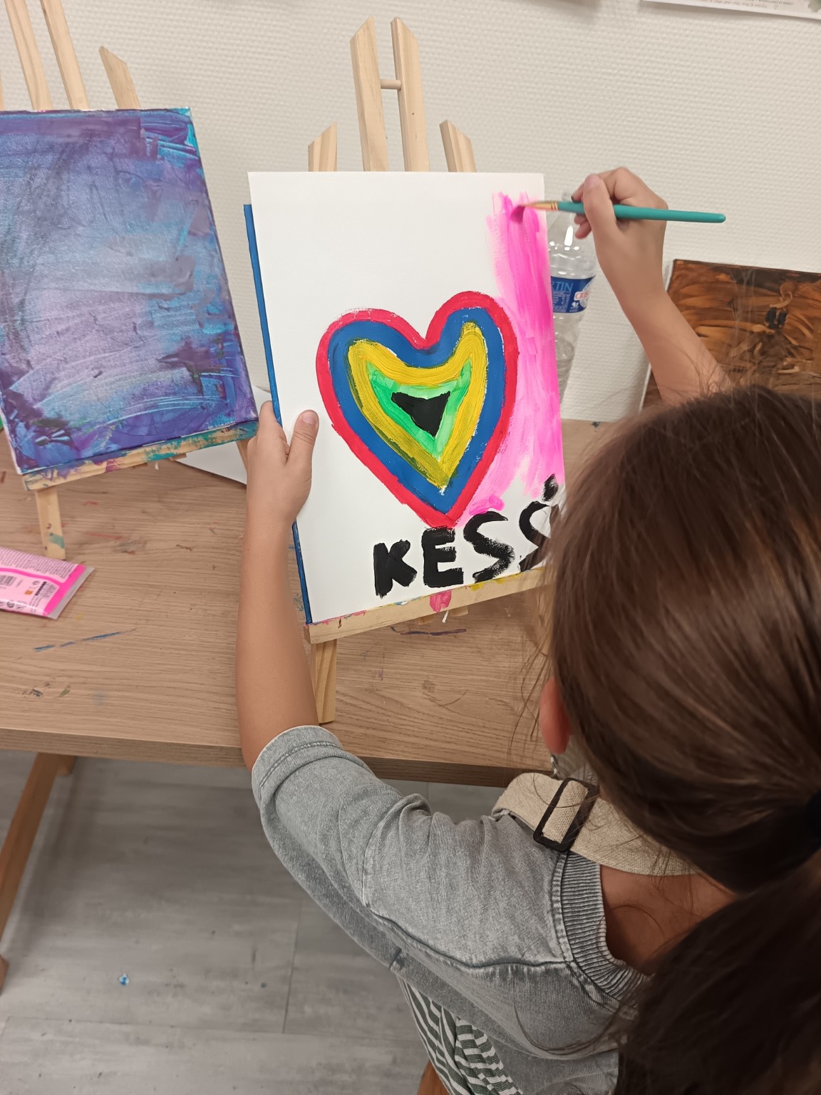 Jeune élève réalisant une peinture colorée en forme de cœur à l'atelier Narin'Art